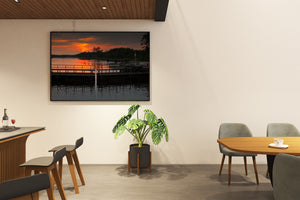 Evening waterway scene with dark lock gates and bright sunset.