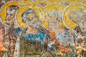 Weathered fresco figures with yellow halos at Voronet, Romania.