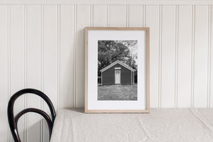 Wabash Township schoolhouse framed by grass and overhanging branches.