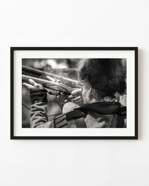 Reenactor firing a musket during a War of 1812 event in black and white.