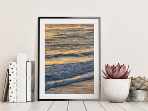 Golden ocean reflections above a curling line of white surf.