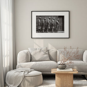 Black and white memorial photograph with textured bronze figures and brickwork.