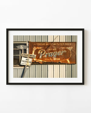 Weathered Atlas Prager beer advertisement with a Route 66 shield