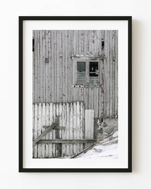 Weathered Norwegian barn wall with a broken window and snow