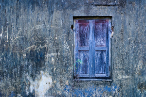 Faded blue shutter surrounded by scratched plaster in India