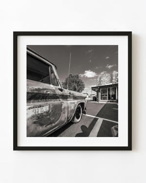 Weathered Chevrolet pickup beside a Route 66 service station in black and white