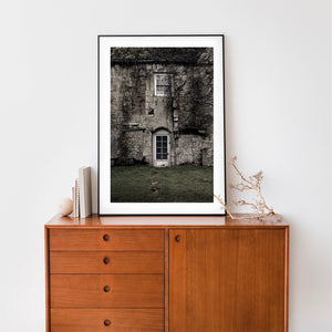 Worn white doorway beneath a window in an old stone house