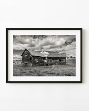 Weathered farm buildings near Hedley beneath a cloudy sky in black and white