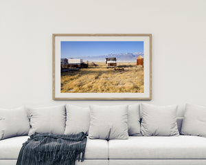 Farmyard with an old truck, sheds and distant snowy peaks
