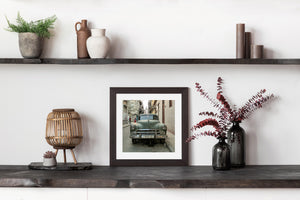 Weathered green sedan parked beside a Havana doorway