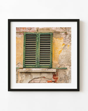 Weathered green shutters on a peeling ochre wall in Tuscany