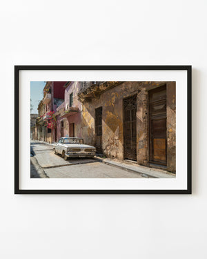 Classic white car parked beside weathered ochre facades in Havana