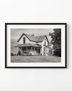 Weathered Indiana farmhouse with a porch swing in black and white