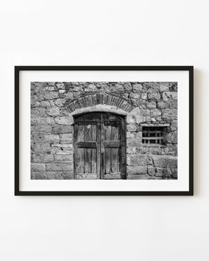 Weathered Italian double door beneath a brick arch in black and white