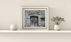 Weathered double doors beside a small boarded wall opening