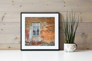 Faded orange wall surrounding a white barred window