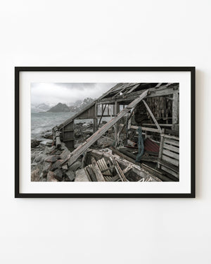 Weathered Lofoten boathouse and old wooden boat beside a Norwegian fjord