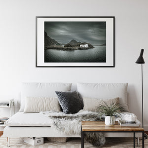 Moody Norwegian waterfront with a white building beside rocky outcrops