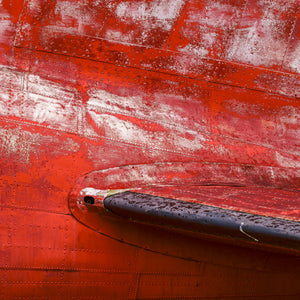 Close-up of red aircraft panels, rivets and worn paint in Alaska