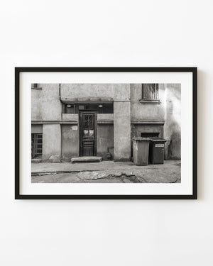 Weathered Romanian doorway and two street bins in black and white
