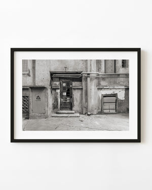 Weathered Romanian doorway beneath exposed pipes in black and white