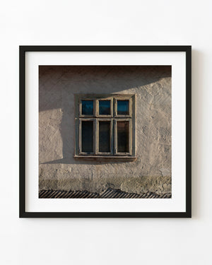 Weathered Romanian farmhouse window in warm light and shadow