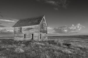 Old wooden farmhouse standing alone in Saskatchewan grassland