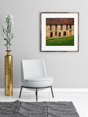 Weathered stone building with brick arches and green grass in France