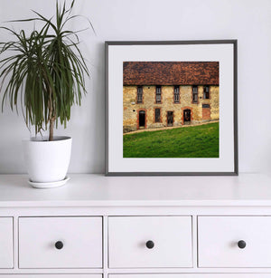 Colour architectural photograph of a rustic French building with a red tiled roof