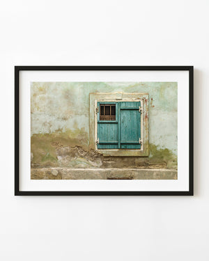 Weathered teal window shutters on a peeling Romanian plaster wall