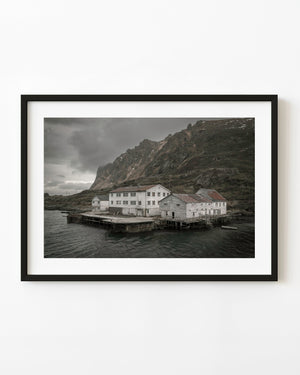 Weathered waterfront hotel beneath steep Norwegian mountains