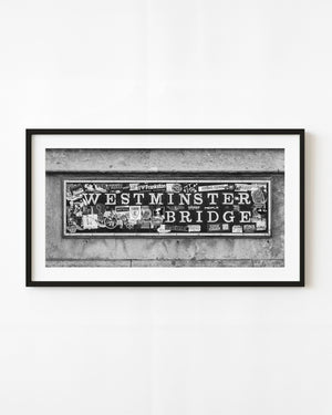 Westminster Bridge sign covered in stickers, photographed in black and white