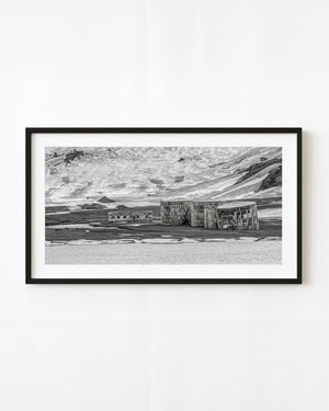 Whalers Bay whaling station and storage tanks beneath snowy hills in black and white