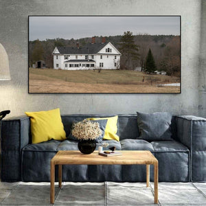 White clapboard house on a grassy slope in rural Maine