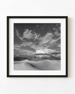 White Sands dunes beneath dramatic clouds in black and white
