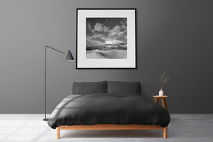Smooth dune ridges and dark mountains beneath a dramatic sky