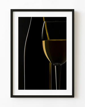 White wine glass and bottle outlined by golden light against black