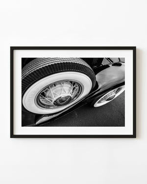 Whitewall wheels and chrome curves on a classic car in black and white