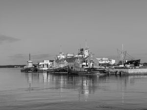 Monochrome harbour photograph of tugboats reflected in calm water