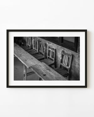 Weathered wooden chairs and a long table in an Ishikawa interior in black and white