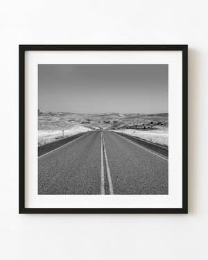 Open Wyoming highway winding through rolling hills in black and white