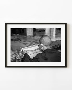 Young monk studying a religious text in Bylakuppe in black and white