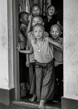 Monochrome portrait of young monks looking out from a temple entrance