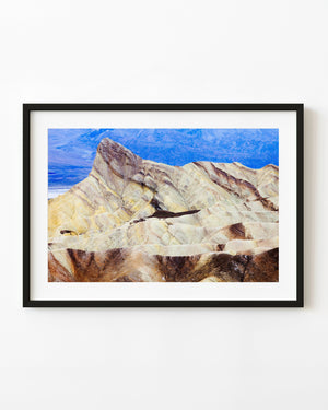 Golden Zabriskie Point ridges against blue mountains in Death Valley