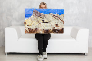 Golden badlands peak contrasting with the blue mountain backdrop at Zabriskie Point