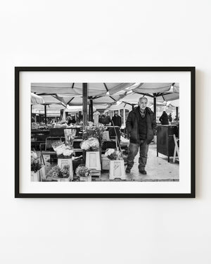 Zagreb flower seller standing beside bouquets in a black and white street photograph
