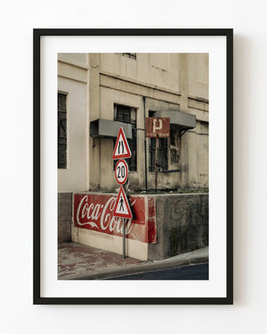 Red road signs and faded Coca-Cola advertising beside a weathered Zagreb building