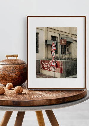 Weathered Coca-Cola lettering beneath road signs and a rusted parking notice