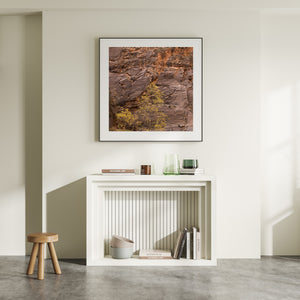 Autumn foliage rising before a broad weathered sandstone wall