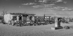 Black and white California Route 66 station with old gas pump and fencing